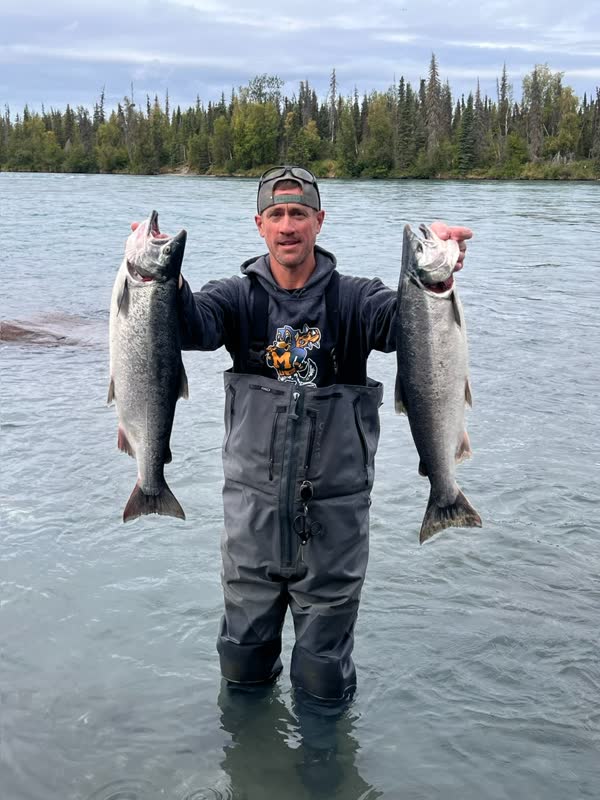 Guide holding two salmon at sunset on the Kenai